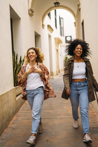 Multikulturelle lachende Frauen beim Spaziergang in der Stadt, lizenzfreies Stockfoto