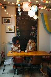 Multikulturelle Frauen im Gespräch in einem Cafe - MPPF00028