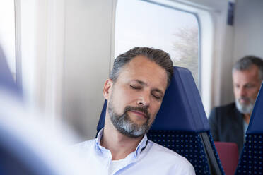 Älterer Mann sitzt im Zug und schläft - FKF03555