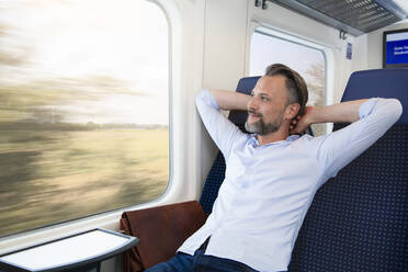 Reifer Mann sitzt im Zug und entspannt sich - FKF03557