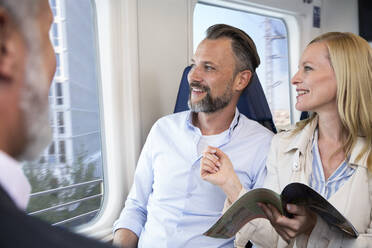 Couple traveling by train, reading magazine - FKF03571