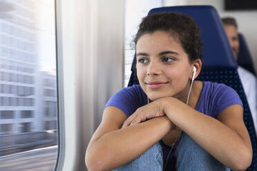 Teenage girl traveling alone by train, listening music - FKF03592