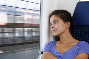 Jugendliches Mädchen reist allein mit dem Zug und schaut aus dem Fenster - FKF03595