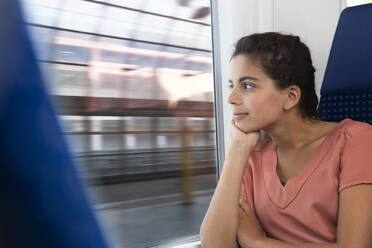 Jugendliches Mädchen reist allein mit dem Zug und schaut aus dem Fenster - FKF03596