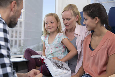 Familie reist mit dem Zug, Töchter lesen ein Buch - FKF03608