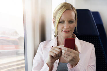 Woman using smartphone on a train - FKF03616