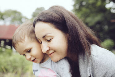 Affectionate mother with toddler in garden - KMKF01033