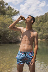 Junger Mann trinkt Bier an einem See, Spanien - ACPF00606