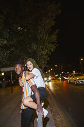 Glückliches junges Paar auf der Straße bei Nacht in der Stadt - LJF00787