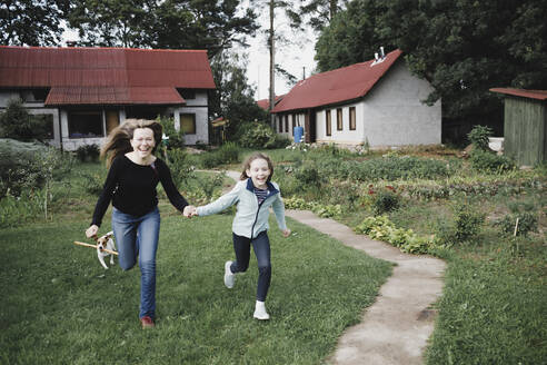 Unbeschwerte Mutter und Tochter laufen im Garten - KMKF01039