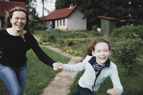 Unbeschwerte Mutter und Tochter laufen im Garten - KMKF01040