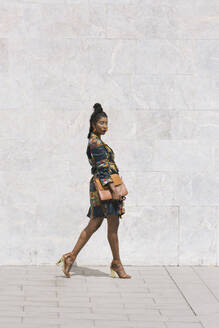 Portrait of chic woman wearing patterned dress walking outdoors - ALBF01001