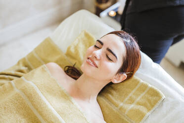 Relaxed young woman lying on massage lounge in a spa - LJF00859