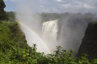 Ein Regenbogen in der Gischt des Victoria-Wasserfalls (Mosi-oa-Tunya), UNESCO-Weltkulturerbe, an der Grenze zwischen Simbabwe und Sambia, Afrika - RHPLF04766