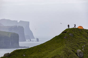 Hikers and tent on cliffs, Kalsoy Island, Faroe Islands, Denmark, Europe - RHPLF04834