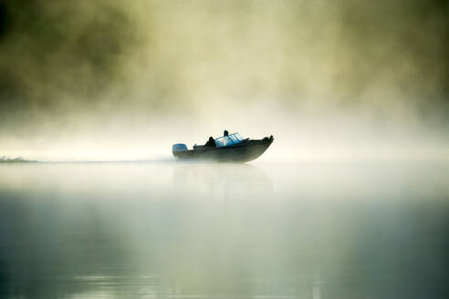 A motorboat navigates the fog on a Minnesota Lake during an early morning, Minnesota, United States of America, North America - RHPLF04932