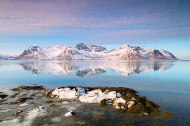 Schneebedeckte Gipfel spiegeln sich im klaren Meer, Grundstad, Lofoten-Inseln, Nordland, Norwegen, Europa - RHPLF05004