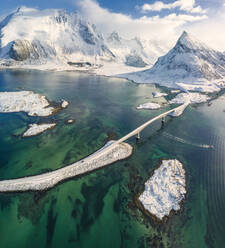 Panoramablick auf den schneebedeckten Gipfel des Volanstinden und die Fredvang-Brücke, Lofoten-Inseln, Nordland, Norwegen, Europa - RHPLF05012