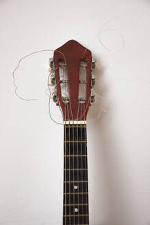 Nahaufnahme einer zerbrochenen Gitarre an einer weißen Wand - JMF00448