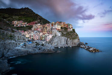 The clouds over Manarola light up with the colours of sunset during a long exposure, Manarola, Cinque Terre, UNESCO World Heritage Site, Liguria, Italy, Europe - RHPLF05222