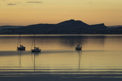 Segelboote bei Sonnenaufgang in Aberdour mit Edinburgh im Hintergrund, Fife, Schottland, Vereinigtes Königreich, Europa - RHPLF05589