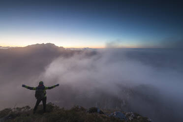 Hiker on top of Monte Coltignone at dawn, province of Lecco, Lombardy, Italy, Europe - RHPLF05698