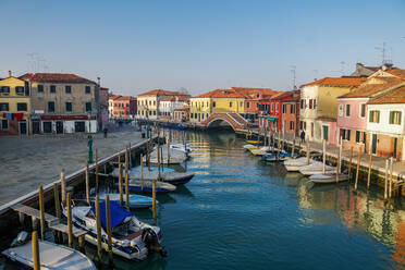 Blick auf die steinerne Brücke Ponte San Martino über den Kanal mit bunten Gebäuden und vertäuten Booten auf hölzernen Kaipfeilern, Venedig, UNESCO-Weltkulturerbe, Venetien, Italien, Europa - RHPLF05862