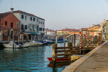 Blick auf die Steinbrücke Ponte San Martino über den Kanal mit bunten Gebäuden und vertäuten Booten auf hölzernen Anlegestellen, Murano, Venedig, UNESCO-Weltkulturerbe, Venetien, Italien, Europa - RHPLF05863