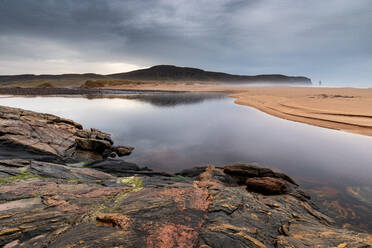 Felsformationen in der Sandwood Bay, mit Am Buachaille sea stack in weiter Ferne, Sutherland, Schottland, Vereinigtes Königreich, Europa - RHPLF06499