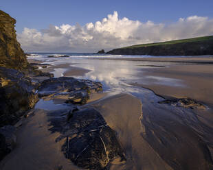 Atlantische Wolken reflektieren das Licht der Morgendämmerung auf den nassen Sand und die Felsen von Trevone in der Nähe von Padstow, Cornwall, England, Vereinigtes Königreich, Europa - RHPLF06643