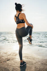 Rear view of a woman stretching her leg on a pier - OYF00004