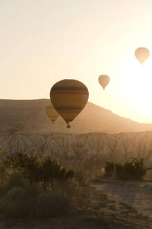 Silhouette Heißluftballons fliegen über Landschaft gegen klaren Himmel während des Sonnenuntergangs in Goreme National Park, Türkei - KNTF03276