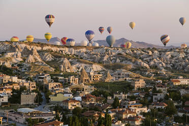 Heißluftballons fliegen über Gebäude gegen den klaren Himmel im Goreme National Park, Kappadokien, Türkei - KNTF03277