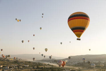 Bunte Heißluftballons fliegen über das Land im Goreme-Nationalpark, Kappadokien, Türkei - KNTF03281