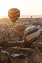 Heißluftballons fliegen über die felsige Landschaft in Goreme bei Sonnenuntergang, Kappadokien, Türkei - KNTF03293