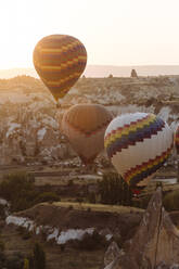 Hot air balloons flying over rocky landscape in Goreme during sunset, Cappadocia, Turkey - KNTF03293