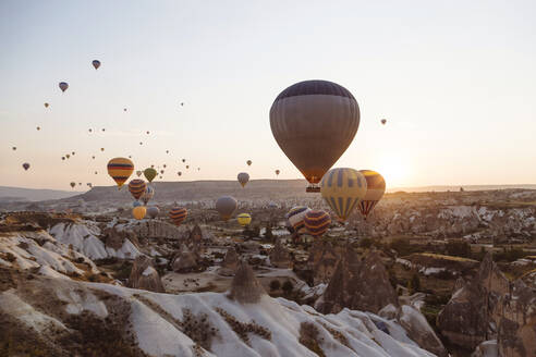 Heißluftballons fliegen über felsige Landschaft gegen klaren Himmel in Goreme während des Sonnenuntergangs, Kappadokien, Türkei - KNTF03294