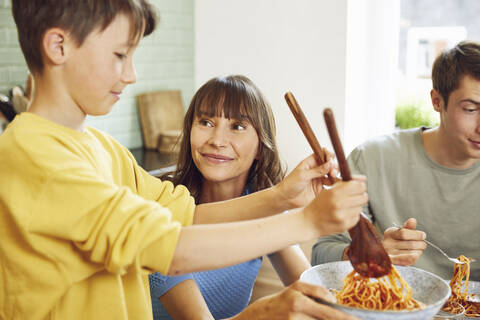 Mutter isst Spaghetti mit ihren Söhnen in der Küche, lizenzfreies Stockfoto