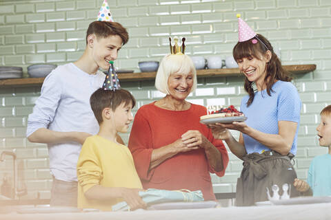 Mutter und Söhne feiern den Geburtstag ihrer Großmutter in ihrer Küche, lizenzfreies Stockfoto