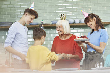 Mother and sons celebrating grandmother's bithday in their kitchen - MCF00203