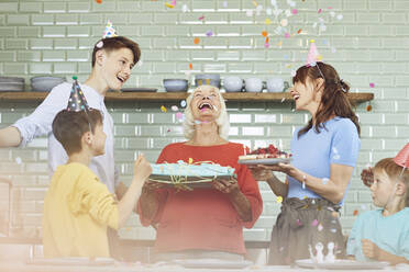 Mother and sons celebrating grandmother's bithday in their kitchen - MCF00204