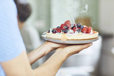 Frau serviert Beerenkuchen bei Geburtstagsfeier, lizenzfreies Stockfoto