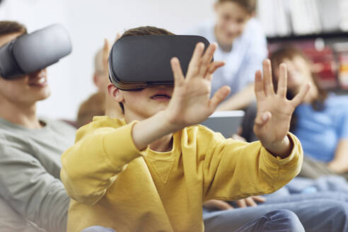 Little boy playing with VR goggles, sittiing on couch with his family - MCF00232