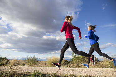 Women running together in countryside - ABZF02538