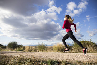 Young woman jogging on road in countryside - ABZF02539