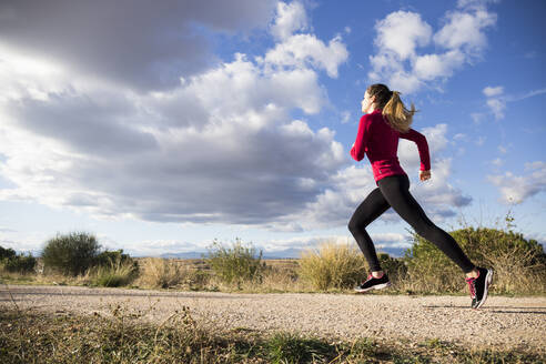 Junge Frau joggt auf der Straße in der Natur - ABZF02539