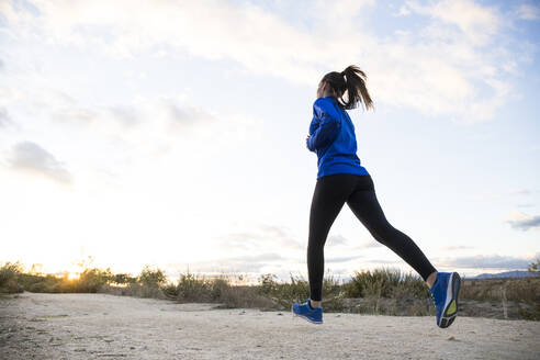 Young woman jogging alone in countryside - ABZF02556