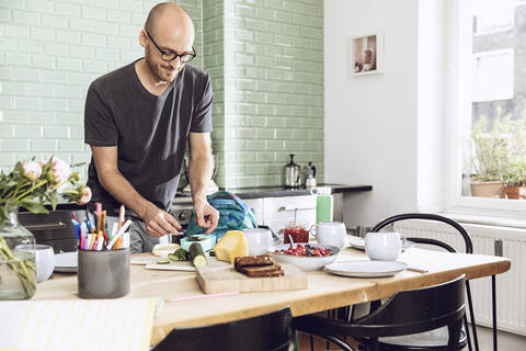 Man in a kitchen packing snacks for lunch break stock photo