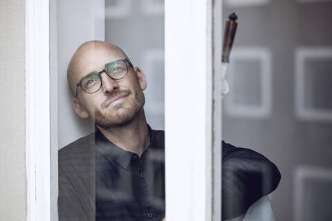 Mann schaut nachdenklich aus dem Fenster, lizenzfreies Stockfoto