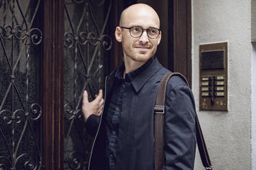 Smiling man on his way to work in front of the entry door - MCF00313